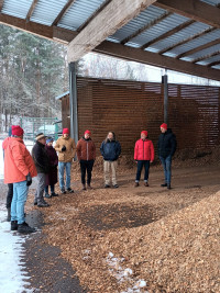 Teilnehmerinnen und Teilnehmer des Informationsbesuchs im HEG-Heizwerk vor den gelagerten Holzhackschnitzeln, die per Radlader der Feuerungsanlage zugeführt werden.